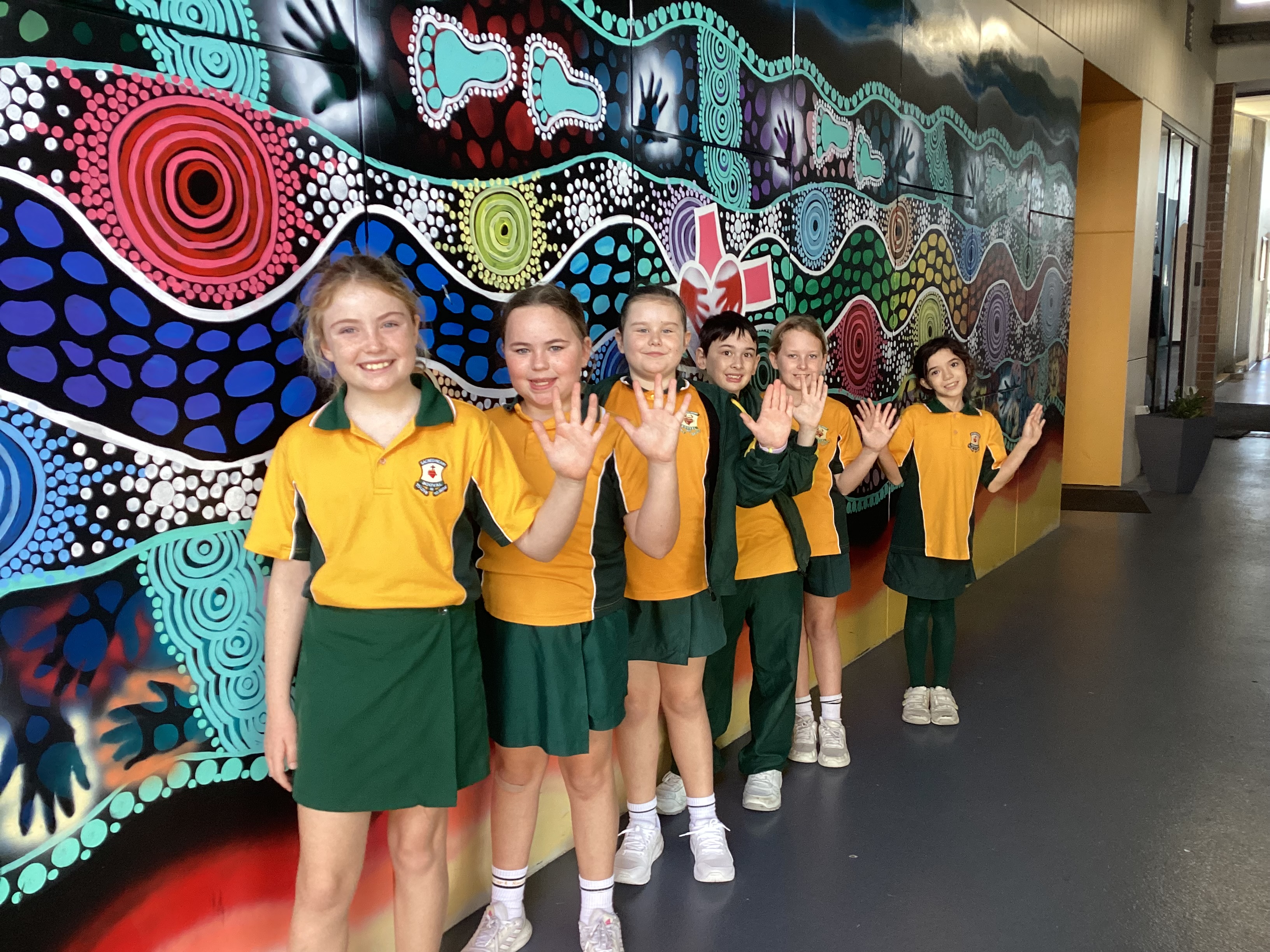 Students standing Infront of the school mural painting