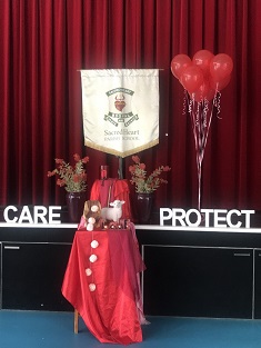 school values display with red backdrop, banner, balloons, and decorated table featuring words care and protect