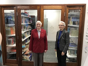staff standing beside preserved historical school records in glass cabinet within library setting